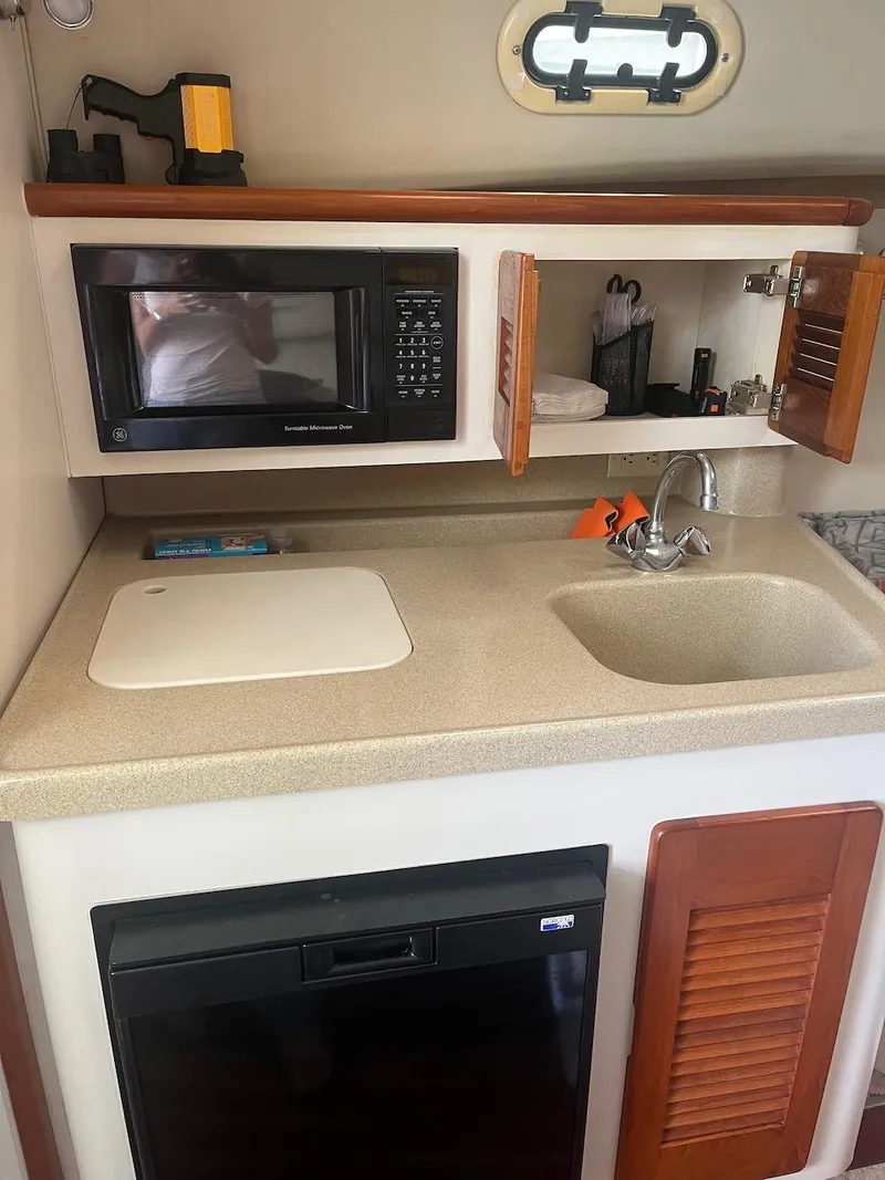 Slide: The Image of 2000 Pursuit 3000 Express boat kitchenette with microwave, sink, and storage cabinets. - 14