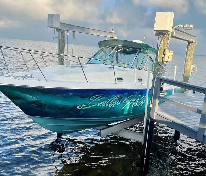 Slide: The Image of 2000 Pursuit 3000 Express boat docked on a lift over water. - 2