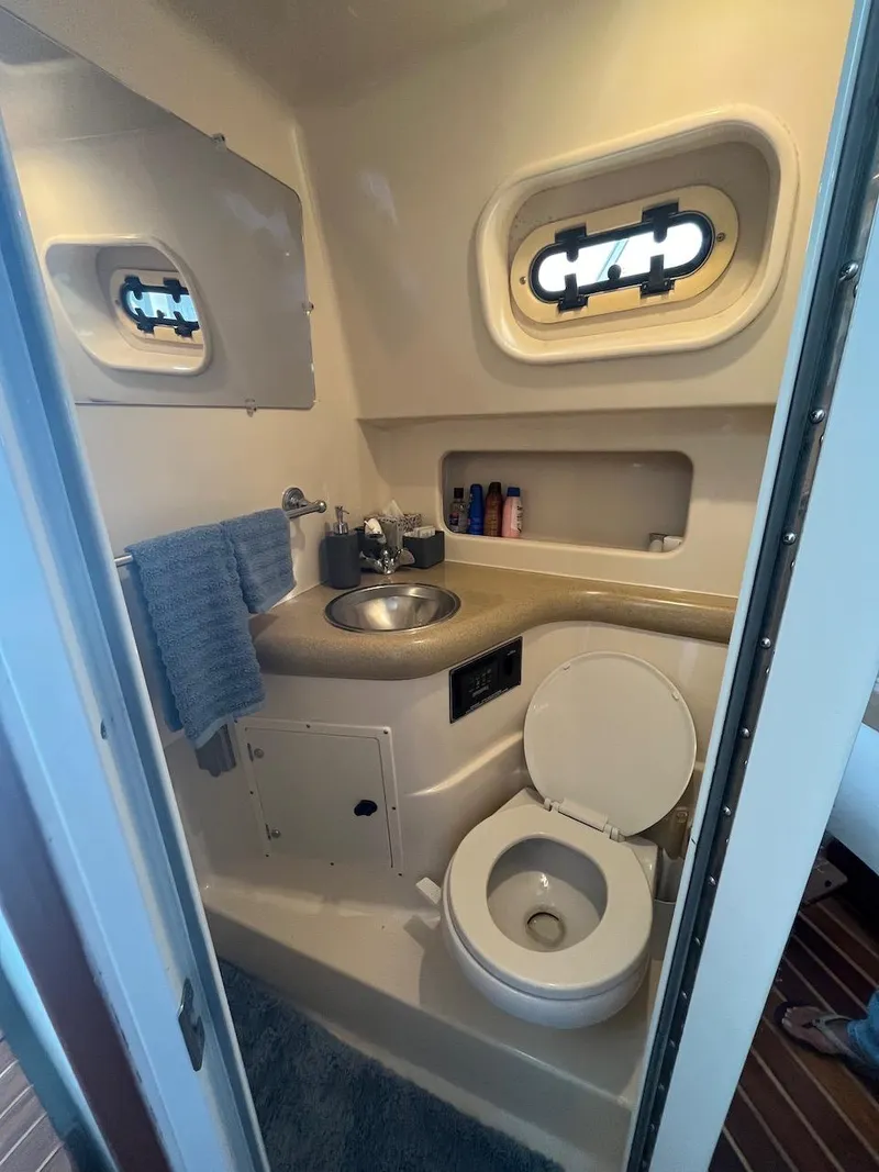 Slide: The Image of Compact bathroom in a 2000 Pursuit 3000 Express boat with sink, toilet, and storage. - 22