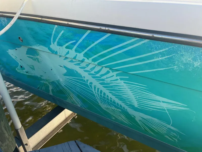 Slide: The Image of Side view of a 2000 Pursuit 3000 Express boat with fish skeleton graphic. - 28