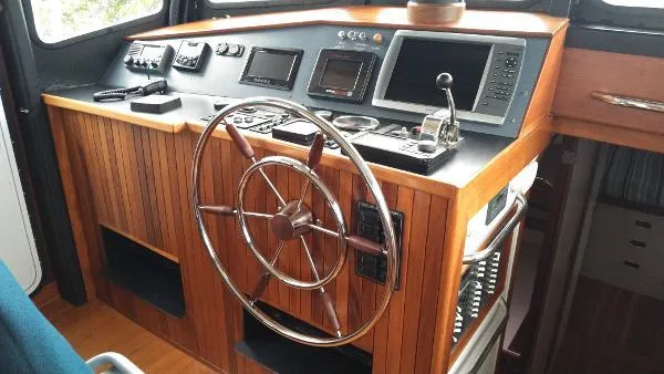 Slide: The Image of 2007 Custom Rockport Steel Trawler MY helm station with wooden wheel and modern navigation equipment. - 26