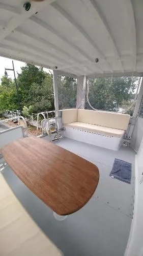 Slide: The Image of Covered deck area of 2007 Custom Rockport Steel Trawler MY with seating and wooden table. - 35