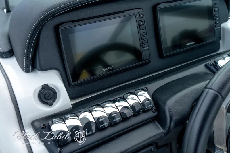 Slide: The Image of 2024 Crownline E305 XS dashboard with dual Garmin displays and control switches. - 23