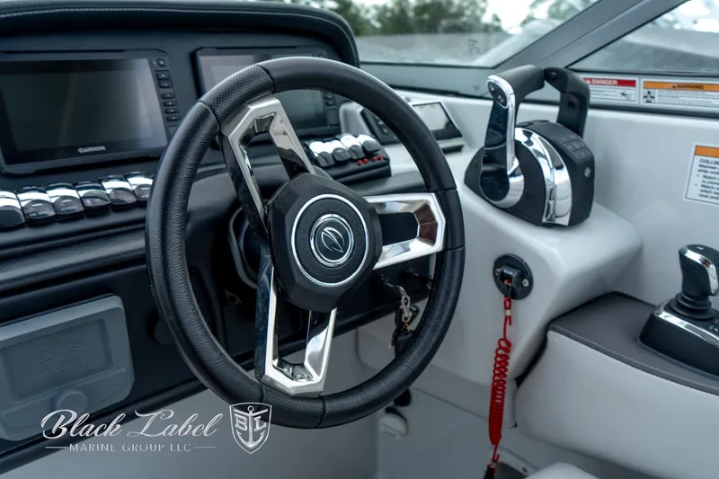 Slide: The Image of 2024 Crownline E305 XS boat cockpit with steering wheel and controls, featuring modern design elements. - 26