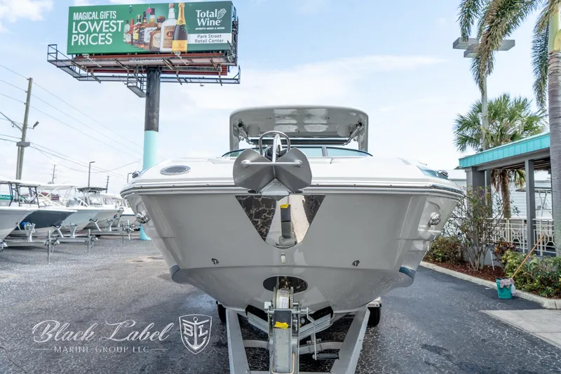 Slide: The Image of 2024 Crownline E305 XS boat displayed at dealership with palm trees and billboard in background. - 3