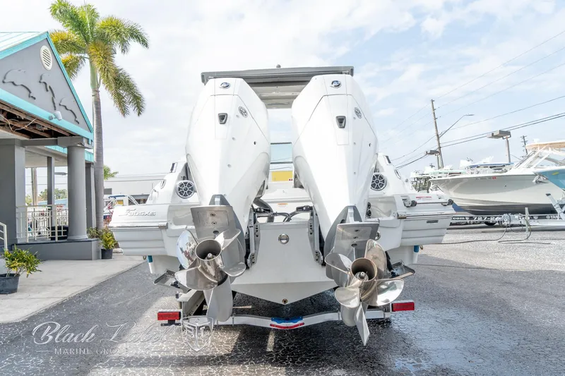 Slide: The Image of 2024 Crownline E305 XS boat with dual outboard motors, parked outdoors. - 5
