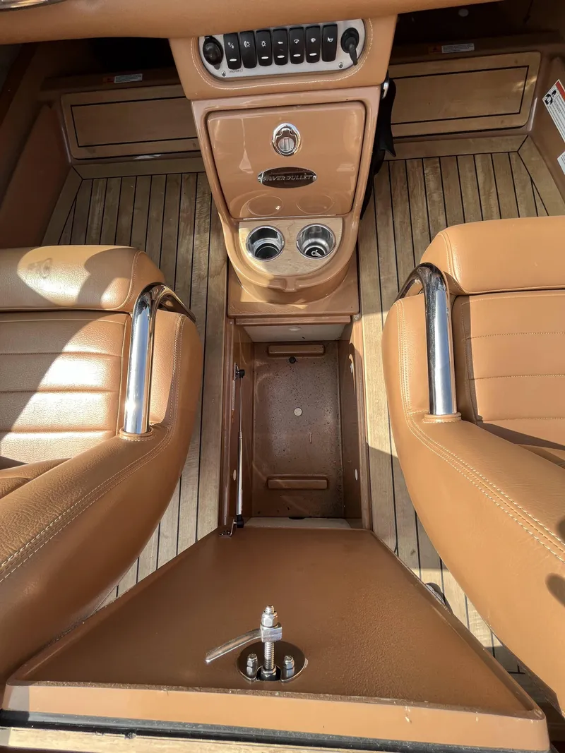Slide: The Image of 2011 Chris-Craft Silver Bullet 20 boat interior with tan leather seats and wooden flooring. - 13