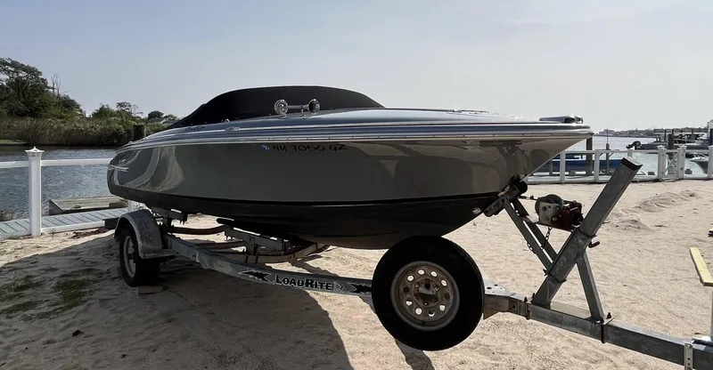 Slide: The Image of 2011 Chris-Craft Silver Bullet 20 boat on a trailer by the water. - 3