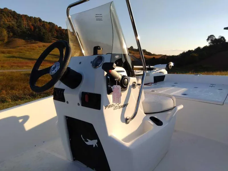 Slide: The Image of 2024 Mako Pro Skiff 15 CC boat console and steering wheel in scenic outdoor setting. - 3