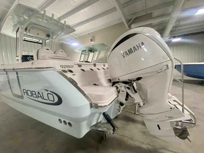 Slide: The Image of 2024 Robalo R250 boat with Yamaha outboard motor in showroom. - 2