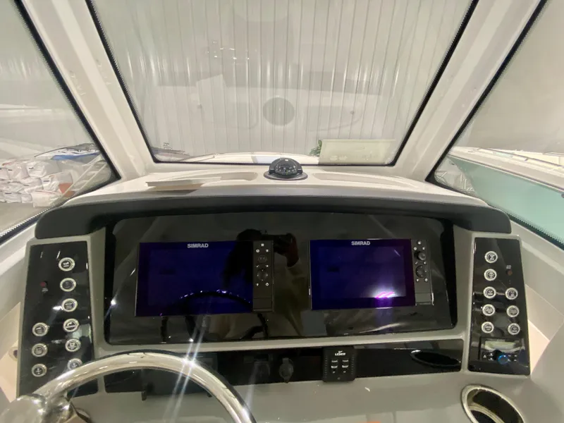 Slide: The Image of 2024 Robalo R250 boat dashboard with dual Simrad displays and control buttons. - 23
