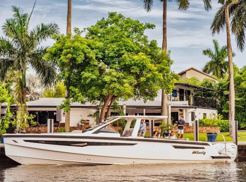 Slide: The Image of 2022 Windy SR44 SX boat docked near a waterfront home with palm trees. - 2