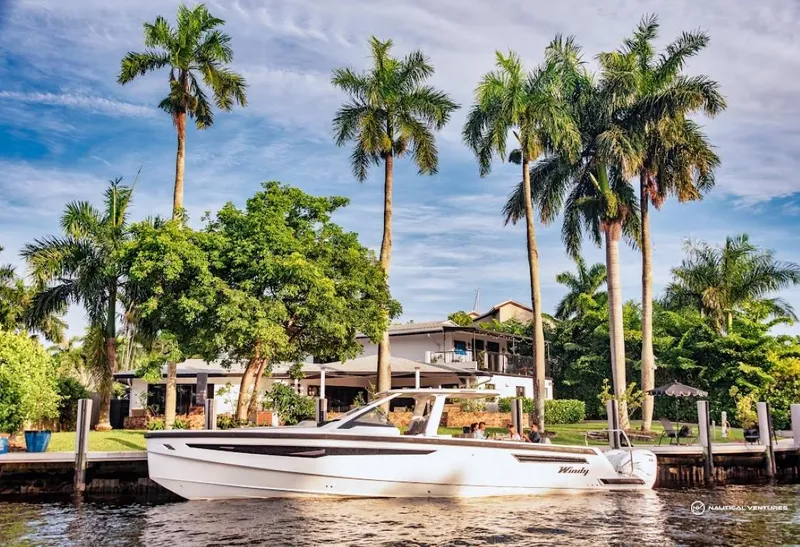 Slide: The Image of 2022 Windy SR44 SX boat cruising near a tropical waterfront home with palm trees. - 1