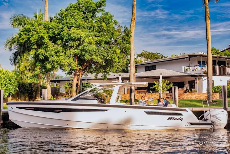 Slide: The Image of 2022 Windy SR44 SX boat docked near a waterfront home with lush greenery. - 4