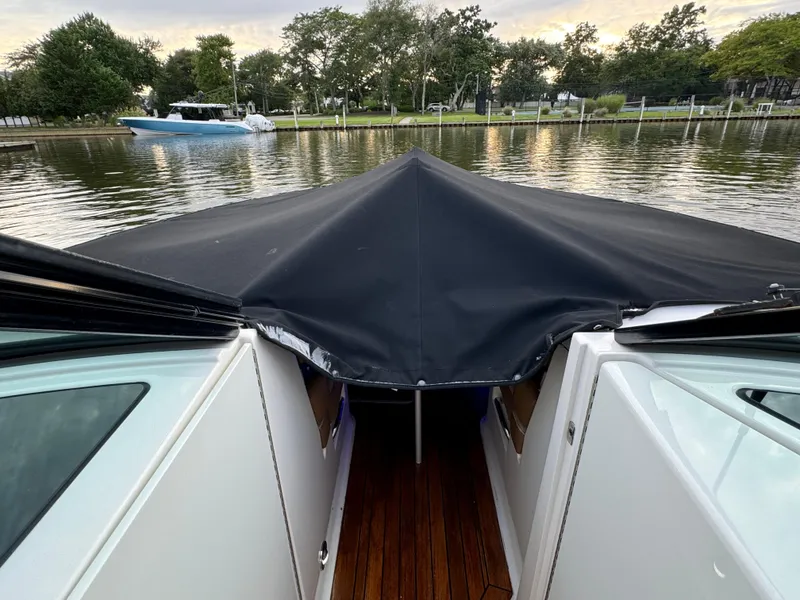 Slide: The Image of 2015 Sea Ray 350 SLX boat with covered bow, docked on a calm lake. - 26