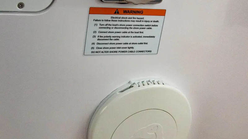 Slide: The Image of Warning label and power outlet on a 2023 Alfastreet 21 Open boat. - 21