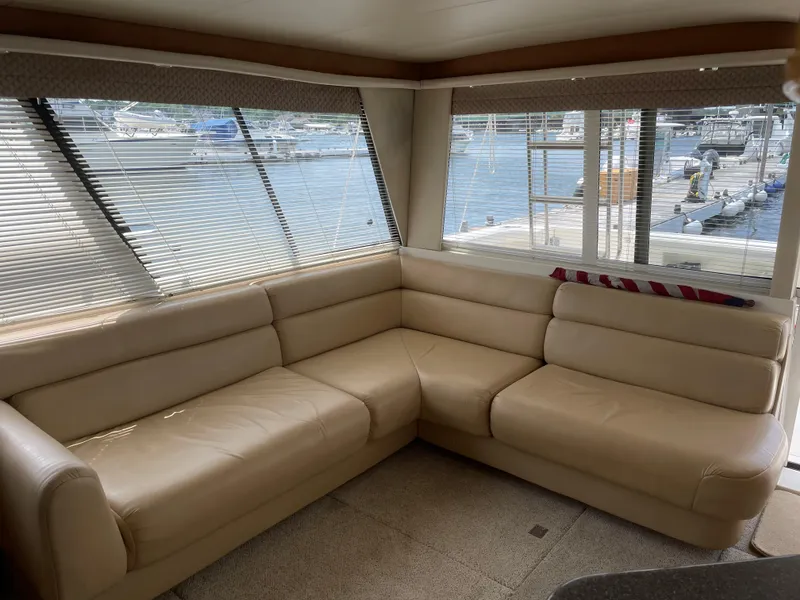 Slide: The Image of 1998 Bayliner 4788 Pilot House Motoryacht interior with beige leather seating and marina view. - 16