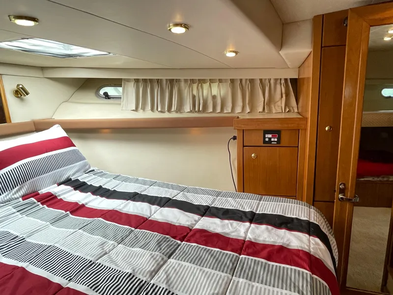 Slide: The Image of 1998 Bayliner 4788 Pilot House Motoryacht bedroom with striped bedding and wooden cabinetry. - 34