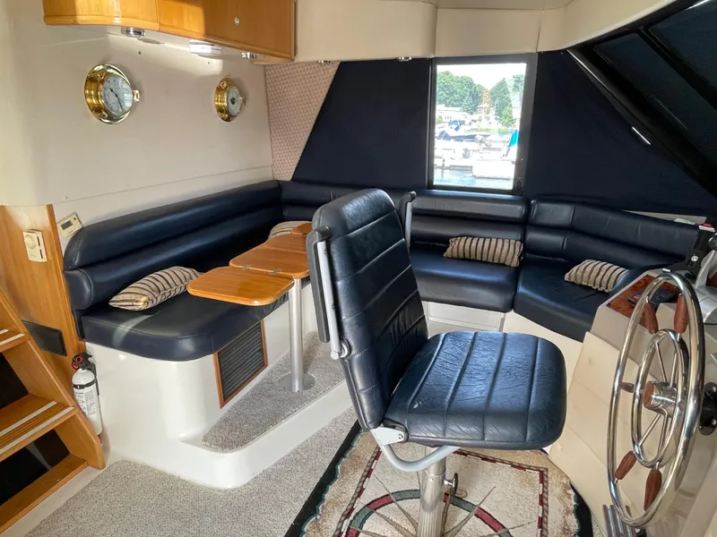 Slide: The Image of 1998 Bayliner 4788 Pilot House Motoryacht interior with black leather seating and wooden accents. - 42