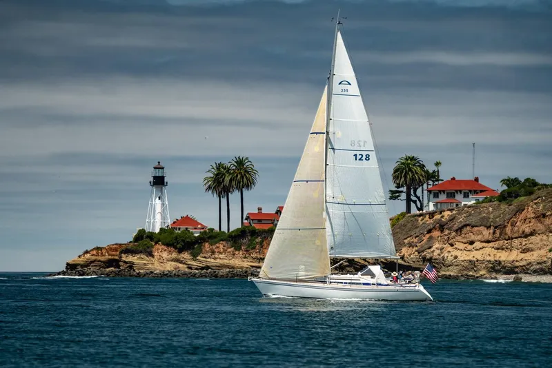 Slide: The Image of Arcona 355 Sloop 2002 sailing near a coastal lighthouse and palm trees. - 0