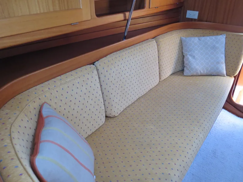 Slide: The Image of Interior seating area of a 2002 Arcona 355 Sloop with cushioned bench and pillows. - 11