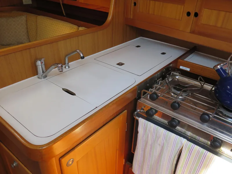 Slide: The Image of Compact kitchen area in a 2002 Arcona 355 Sloop sailboat with stove and sink. - 18