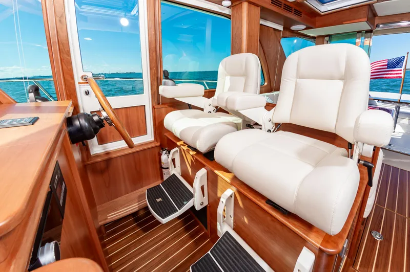 Slide: The Image of Interior helm of 2024 Sabre 43 Salon Express yacht with white leather seats and wooden accents. - 32