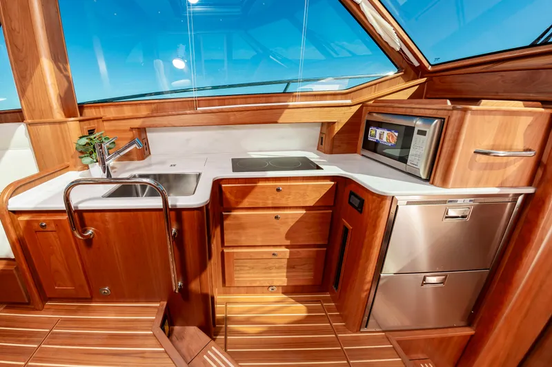 Slide: The Image of Modern kitchen area in 2024 Sabre 43 Salon Express yacht with wood cabinetry and stainless steel appliances. - 40