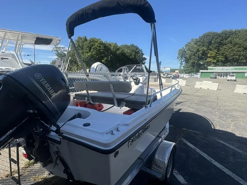 Slide: The Image of 2024 Edgewater 158CS boat with Yamaha motor on trailer, parked outdoors. - 2