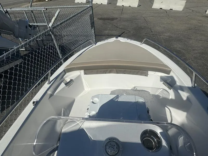 Slide: The Image of 2024 Edgewater 158CS boat with beige seating, docked near a chain-link fence. - 5