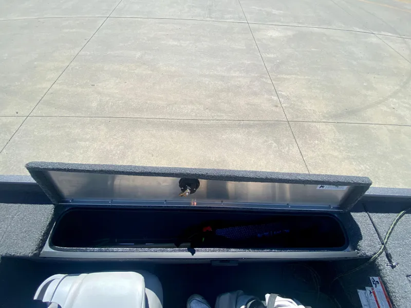 Slide: The Image of 2023 Crestliner 1600 Storm boat storage compartment open on concrete surface. - 17