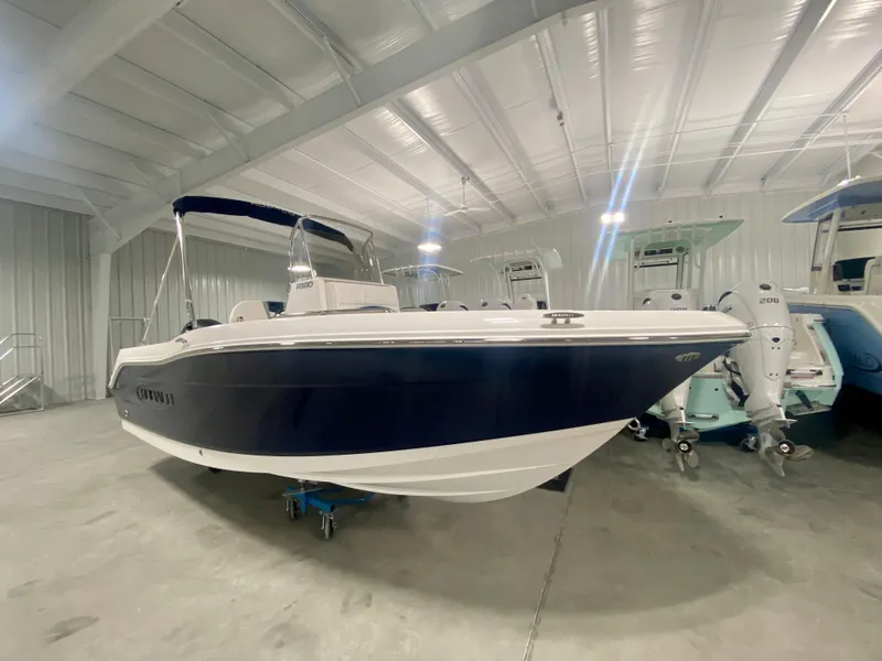 Slide: The Image of 2024 Robalo R180 Center Console boat in a showroom. - 1