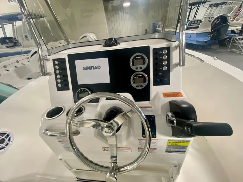 Slide: The Image of 2024 Robalo R180 Center Console boat dashboard with Simrad display and steering wheel. - 8