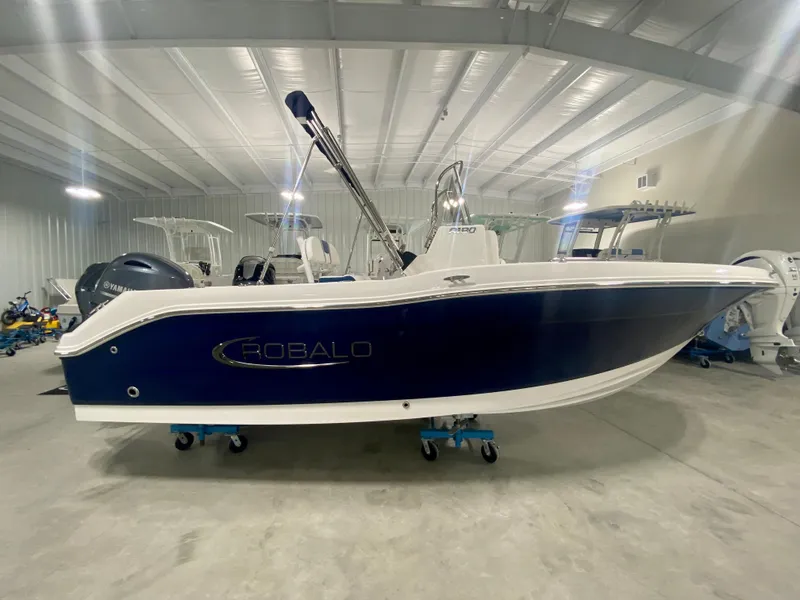 Slide: The Image of 2024 Robalo R180 Center Console boat in a showroom. - 0