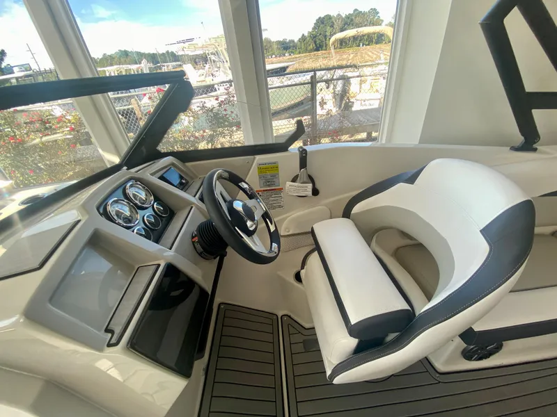 Slide: The Image of 2024 Starcraft SVX 230 OB boat cockpit with steering wheel and captain's chair. - 13