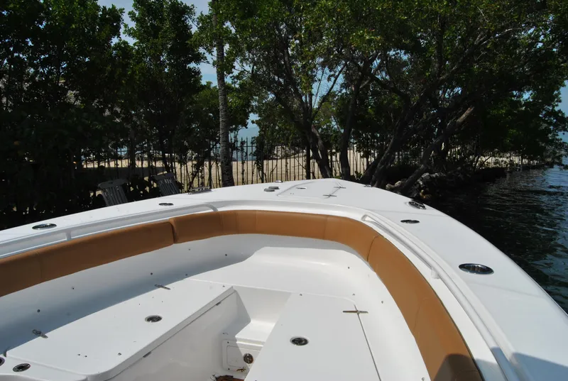 Slide: The Image of 2020 Sea Hunt Gamefish 30 boat with tan seating, docked near lush trees. - 11