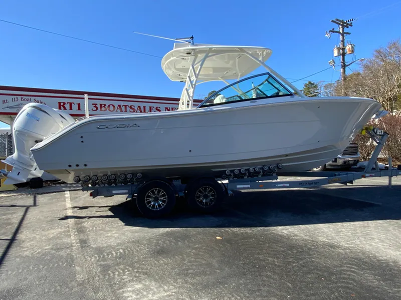 The Image of 2025 Cobia 280 Dual Console boat on trailer at dealership. - 1