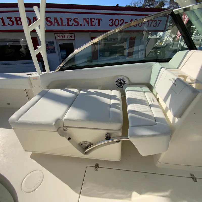 Slide: The Image of 2025 Cobia 280 Dual Console boat interior with white seating and sales office background. - 22