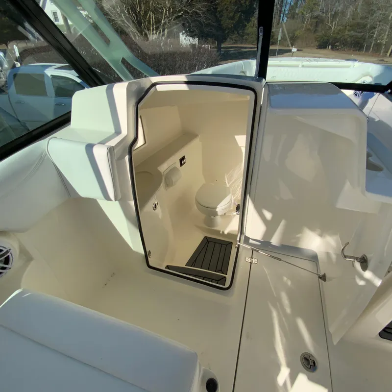 Slide: The Image of 2025 Cobia 280 Dual Console boat interior with open restroom door. - 24