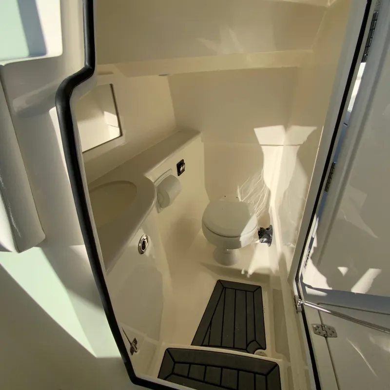 Slide: The Image of Interior of 2025 Cobia 280 Dual Console boat bathroom with toilet and sink. - 25