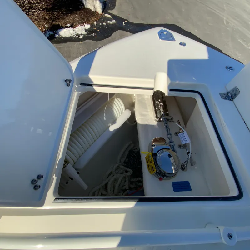 Slide: The Image of Open storage compartment on 2025 Cobia 280 Dual Console boat, showing anchor and rope. - 31