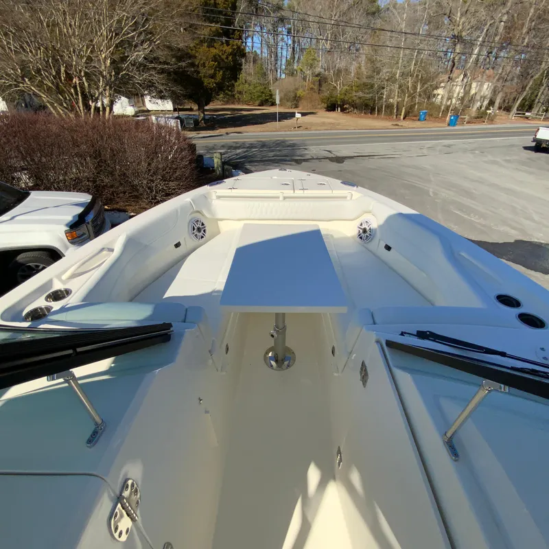 Slide: The Image of 2025 Cobia 280 Dual Console boat with spacious seating and table, parked outdoors. - 37