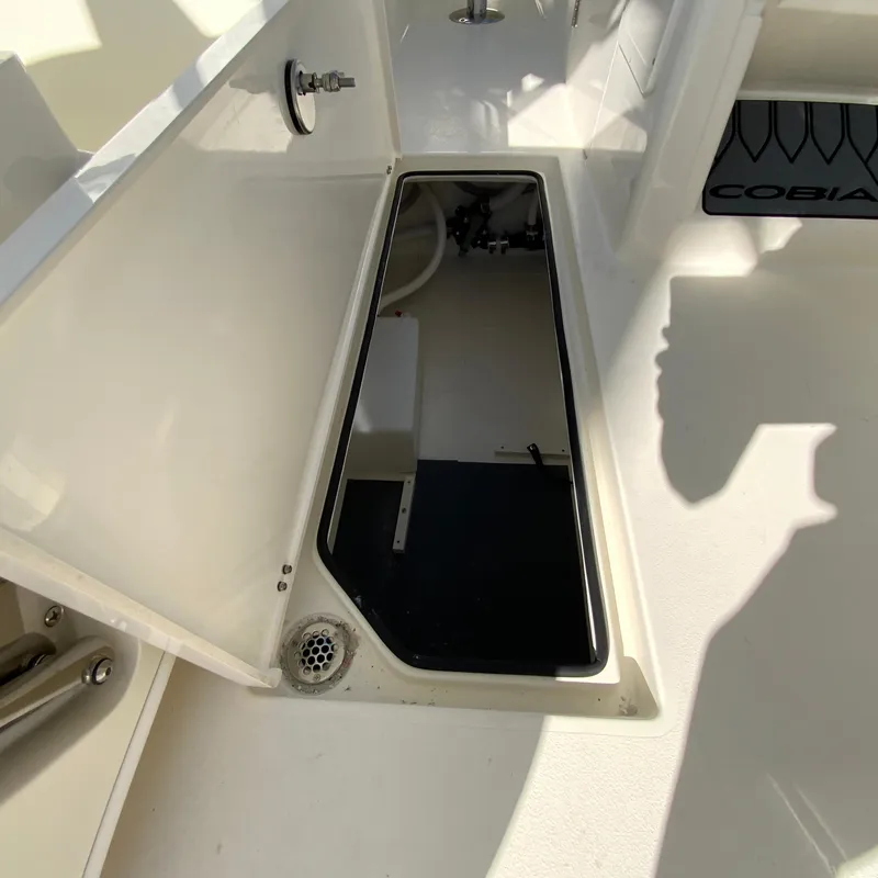 Slide: The Image of 2025 Cobia 280 Dual Console boat storage compartment, open hatch, and interior view. - 38