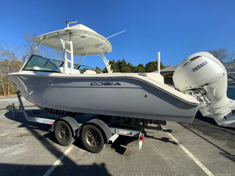 Slide: The Image of 2025 Cobia 280 Dual Console boat on trailer, side view, clear sky background. - 8