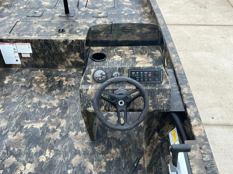 Slide: The Image of 2024 Lund 1870 Predator SC boat interior with camouflage design and steering console. - 18