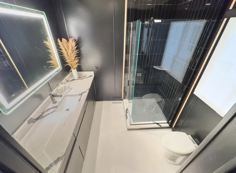Slide: The Image of Modern bathroom with glass shower, illuminated mirror, and sleek black and white design. - 35
