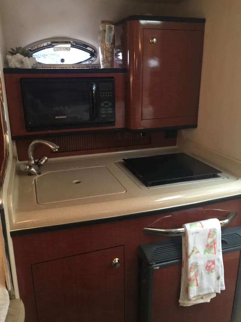 Slide: The Image of 2004 Sea Ray 280 Sundancer galley with microwave, sink, and stove. - 12
