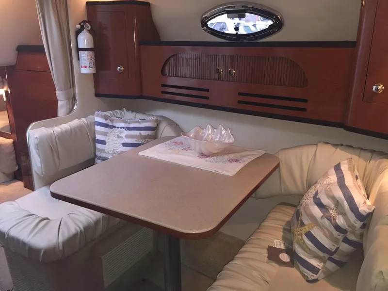 Slide: The Image of 2004 Sea Ray 280 Sundancer cabin interior with dining table and cushioned seating. - 13