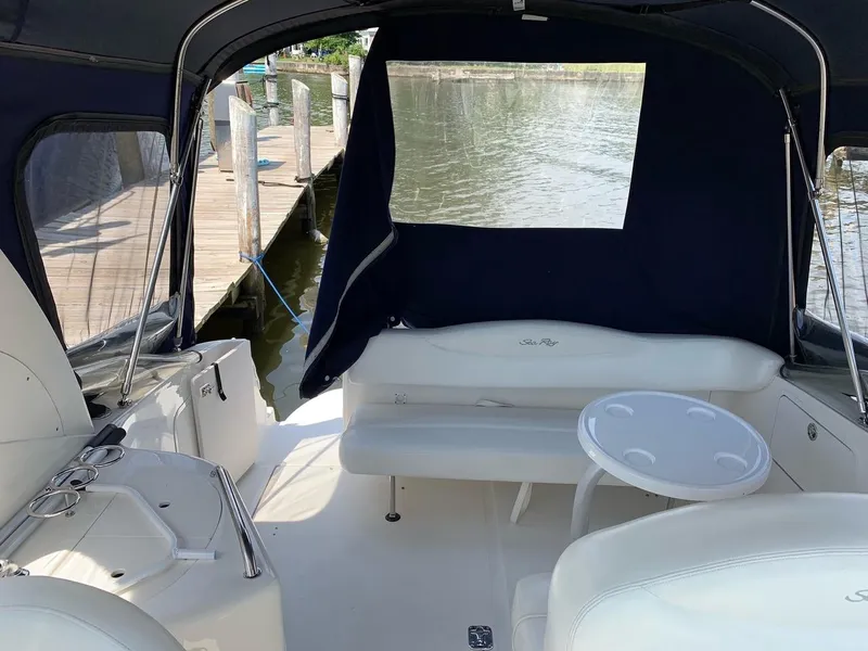 Slide: The Image of 2004 Sea Ray 280 Sundancer boat interior with seating and table, docked by the water. - 5