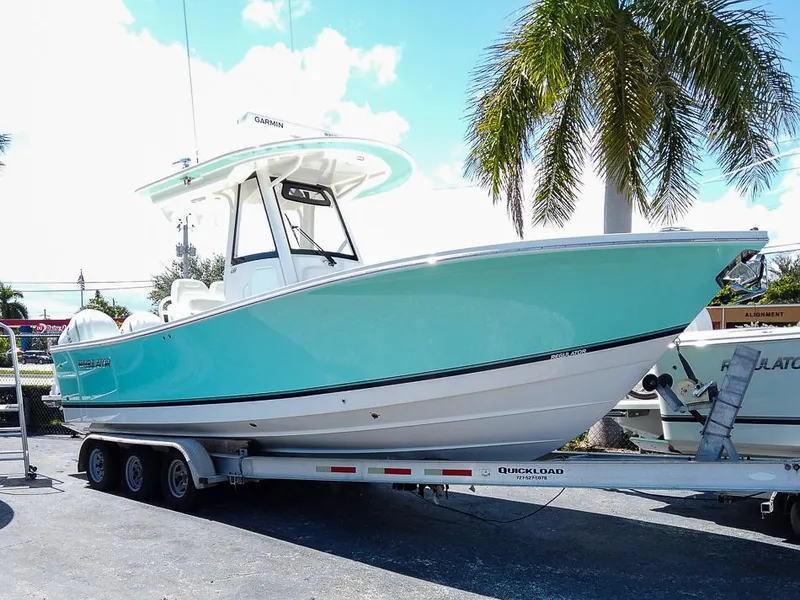 Slide: The Image of 2024 Regulator 28 boat on trailer, turquoise hull, palm tree background. - 0